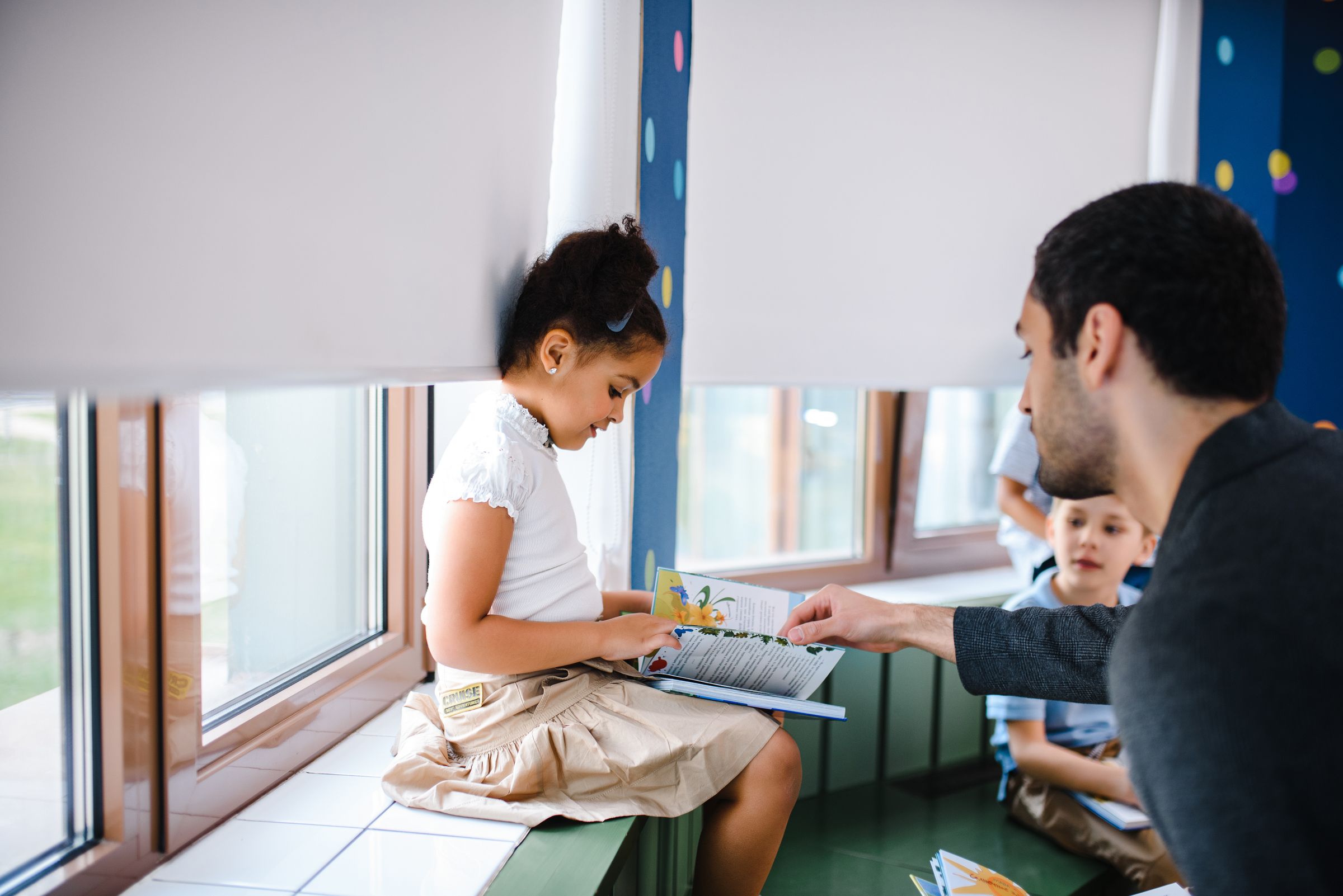 Illustrative photo: A teacher helping a young student read