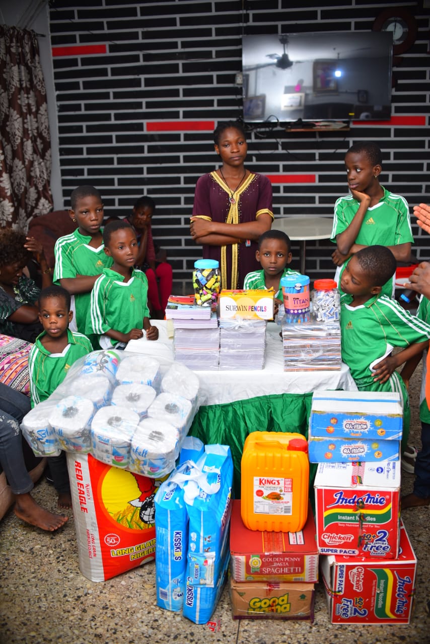 Children in green uniforms standing beside donated essentials