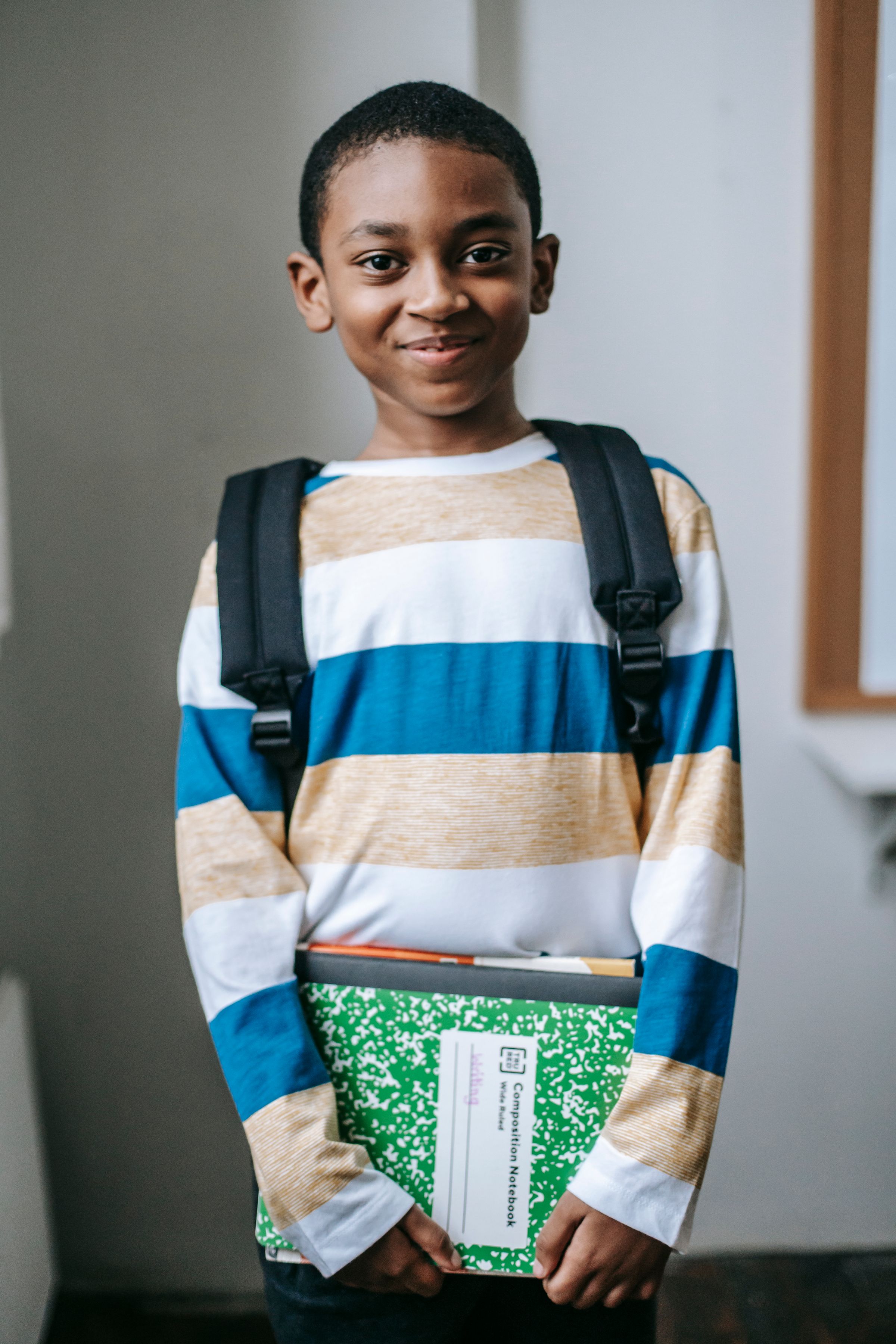Illustrative photo: A smiling schoolboy holding his learning materials