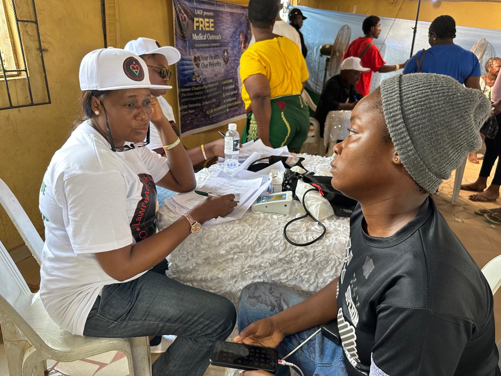 A LAOF volunteer checking a participant’s blood pressure at a table