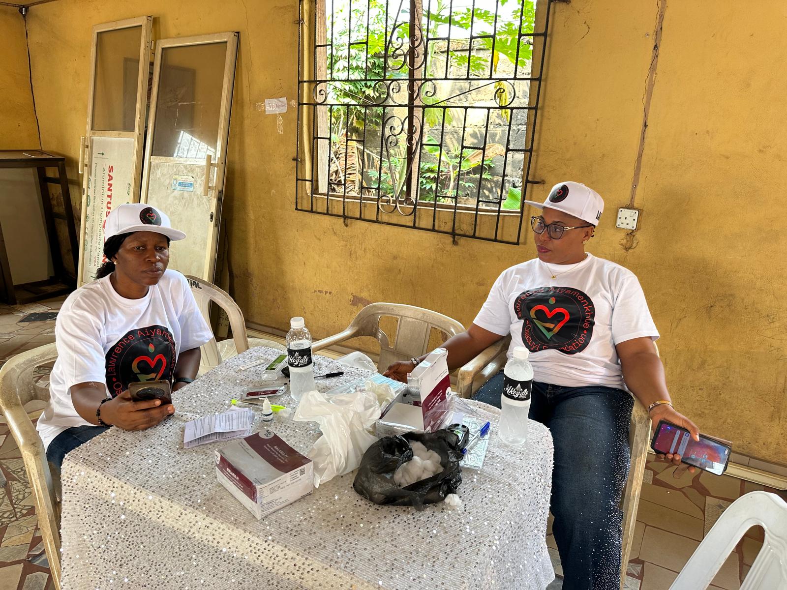 Two LAOF volunteers seated with supplies at an outreach venue