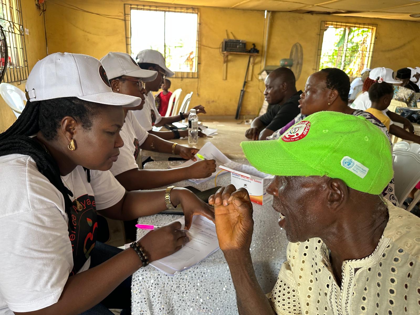 A LAOF volunteer providing a health check to a participant in a green cap
