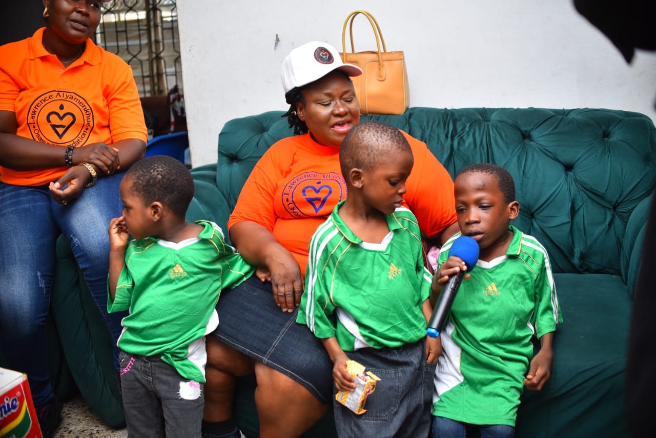 A LAOF volunteer sitting with children in green uniforms