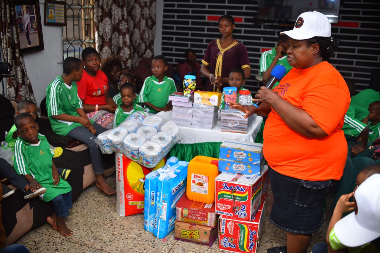 A LAOF volunteer addressing children beside a table of supplies