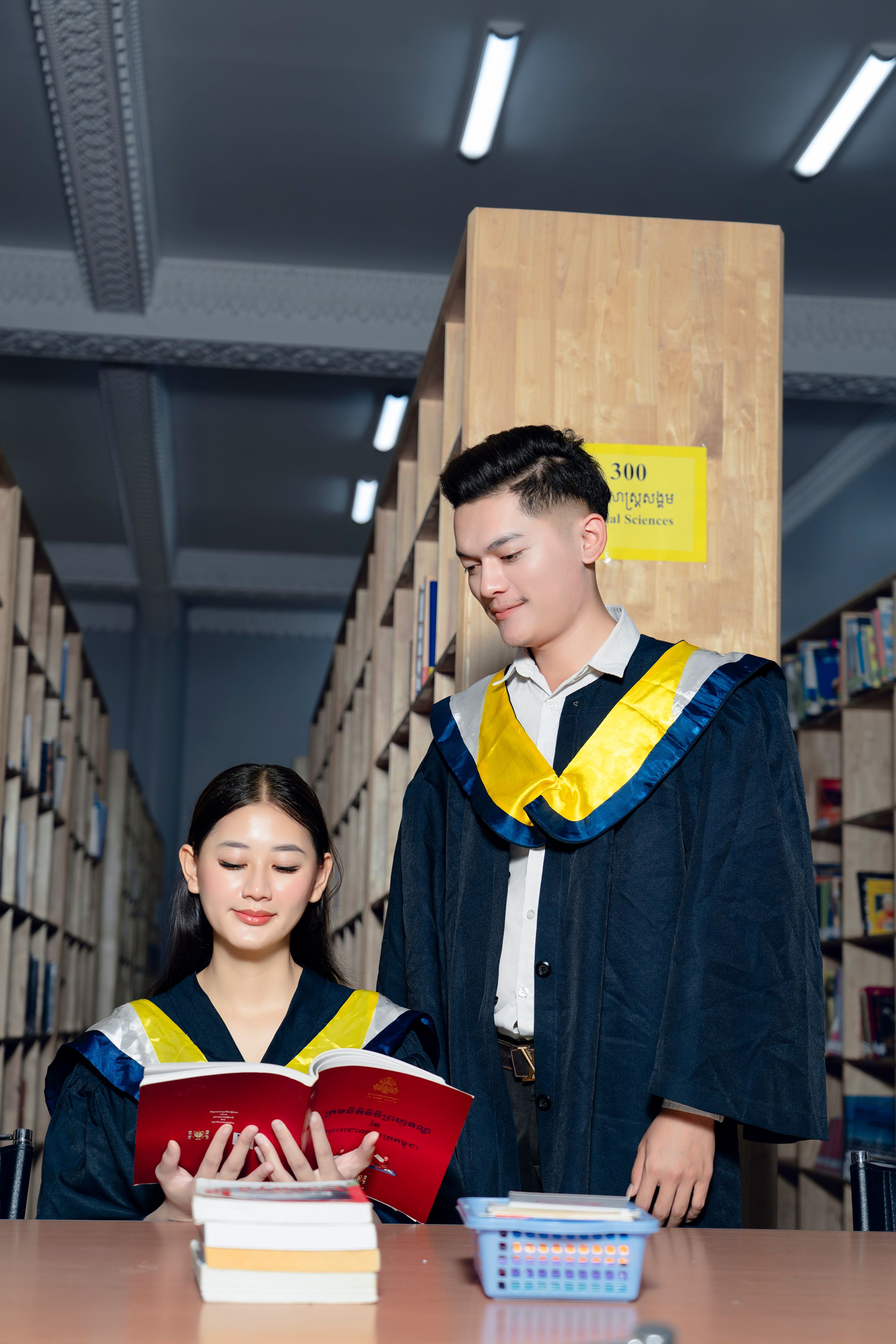 Illustrative photo: Two graduates with books in a library